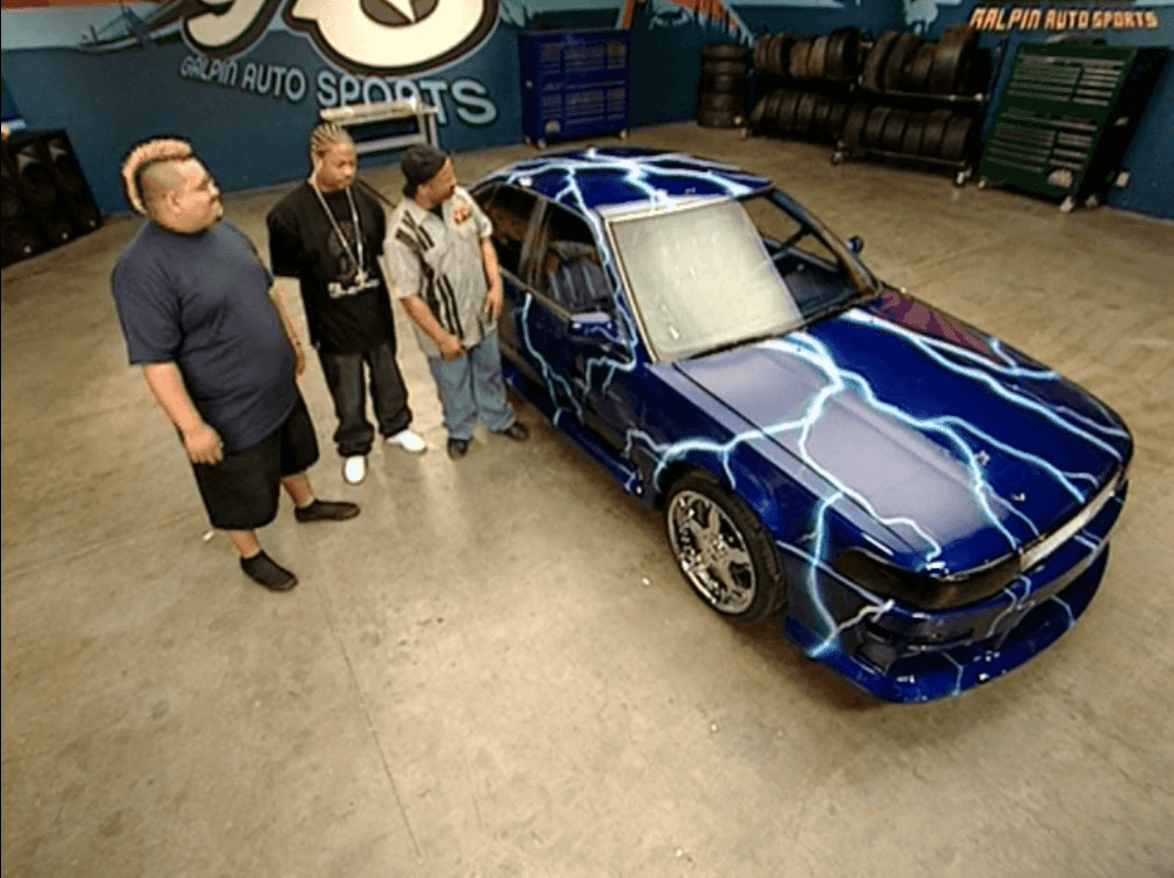 three guys standing next to a car wrapped in lightningbolts