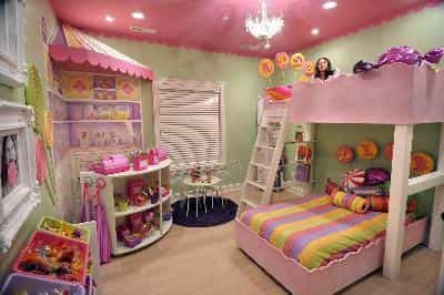 A pink and green painted childrens bedroom decorated with alot of dolls and toys